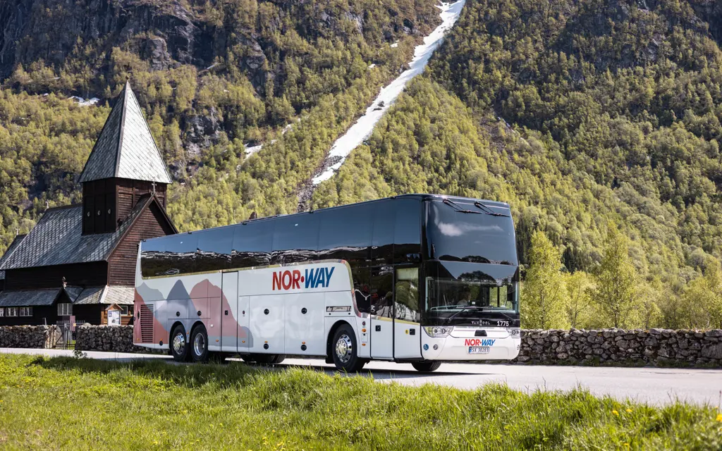 Bilde av buss foran stavkirke