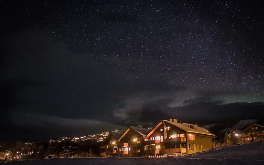 Stjernehimmel over snølandskap og bygninger