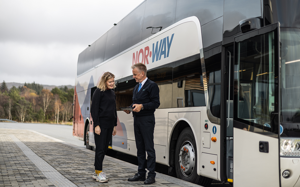 Passasjer og bussjåfør snakker sammen utenfor buss