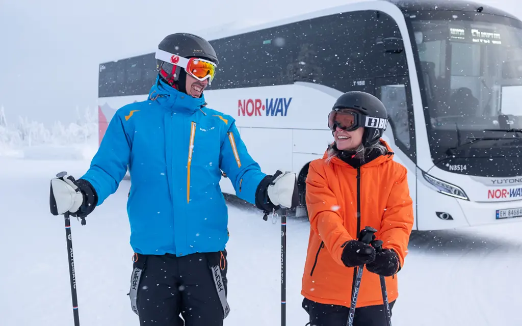 Mann og kvinne i skiutstyr foran NW130 Trysilekspressen