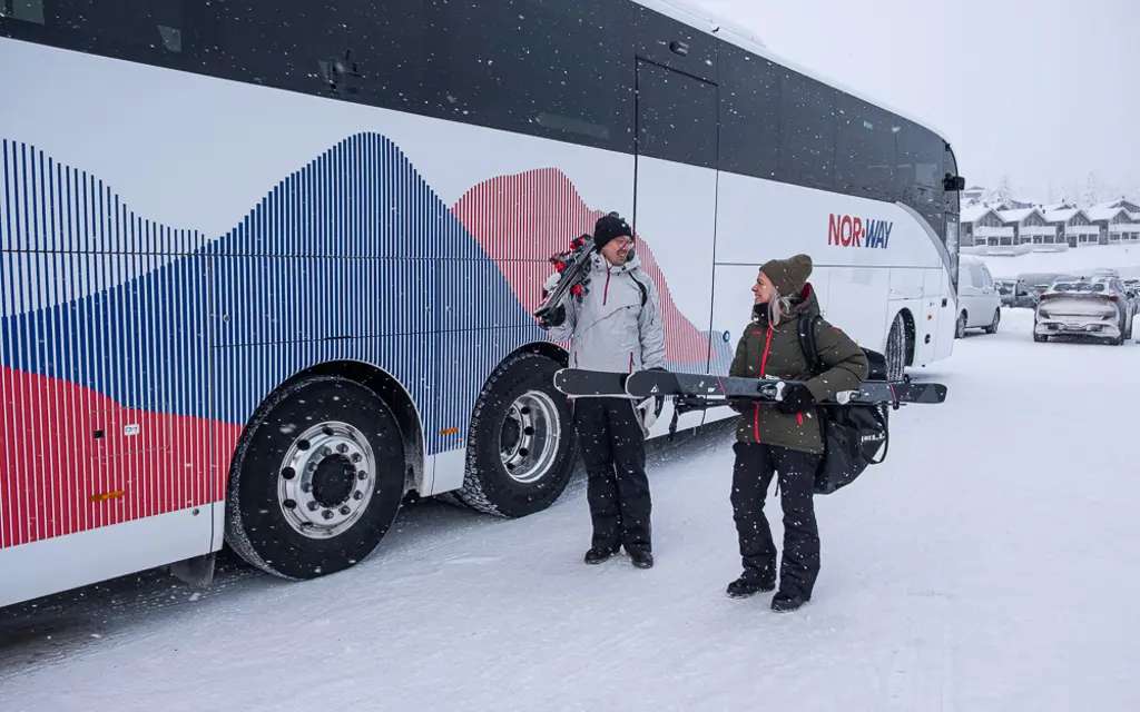 Mann og kvinne med skiutstyr utenfor NW130 Trysilekspressen
